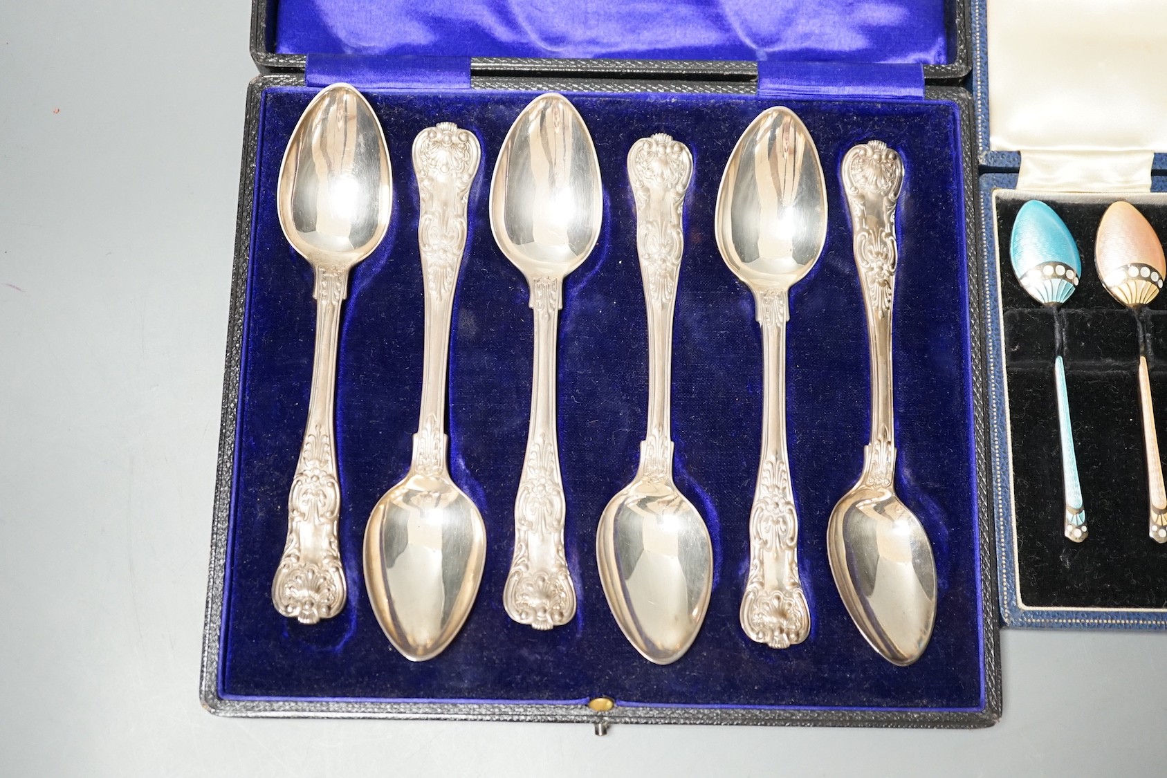 A cased set of six 1960's silver and polychrome enamelled coffee spoons, Turner & Simpson, 97mm and a case set of six William IV silver Kings pattern teaspoons, London, 1835, 14.3cm.